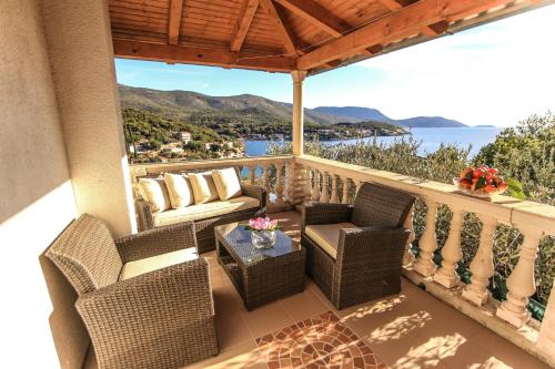 a balcony with chairs and a table with a view of the water at Marivo Guest House in Molunat