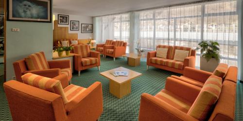 a waiting room with orange chairs and a table at Residence Kristall in Mezzana