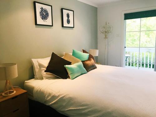Un dormitorio con una cama blanca con almohadas. en Bowral Escape, en Burradoo