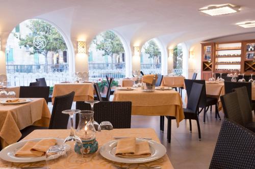 una sala da pranzo con tavoli, sedie e tavolo di Hotel La Pergola a Santa Maria di Castellabate