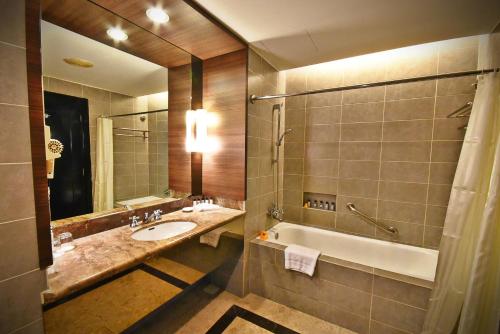 a bathroom with a sink and a bath tub and a mirror at Thistle Port Dickson Resort in Port Dickson