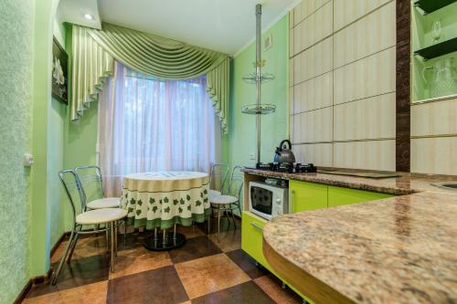 eine Küche mit grünen Schränken sowie einem Tisch und Stühlen in der Unterkunft Apartment on Riverfront of Dnepr in Dnipro
