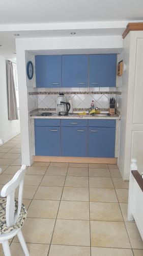 a kitchen with blue cabinets and a white chair at Harz Stolberg Ferienwohnung in Stolberg i. Harz