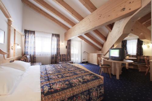 a hotel room with a bed and a television at Hotel Alpi in Campitello di Fassa