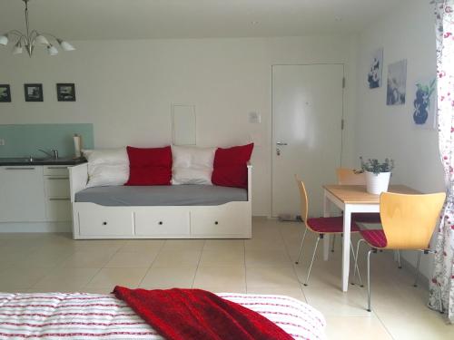 a bedroom with a bed with red pillows and a table at Charming Studio near Rotsee Lucerne Kitchen/WiFi/Wasching machine in Luzern