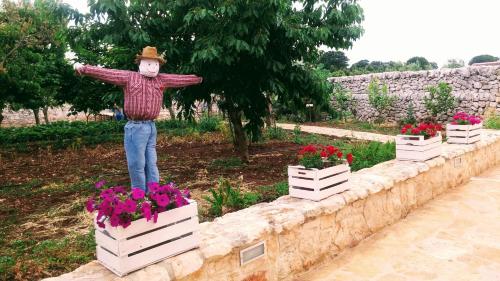 a statue of a man standing on a wall with flowers at Masseria Peppeturro in Cisternino