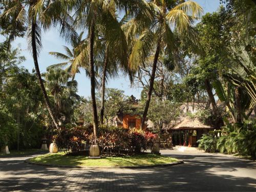 a driveway with palm trees and a house at Puri Santrian Beach Resort And Spa in Sanur