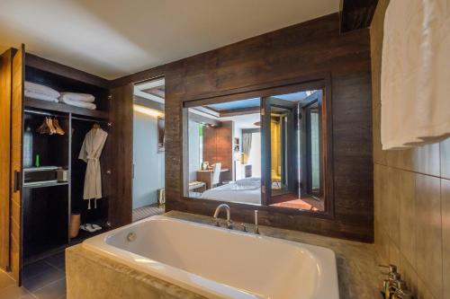 a bathroom with a tub and a large mirror at Naina Resort & Spa - SHA Extra Plus in Patong Beach