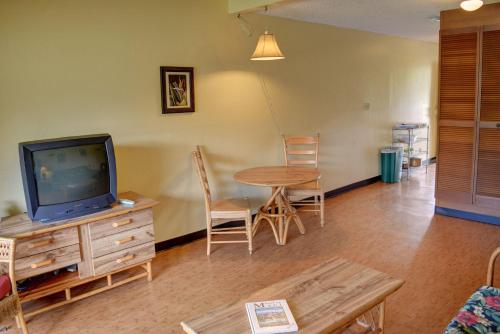 a living room with a table and a tv at Kihei Bay Surf 117 in Kihei