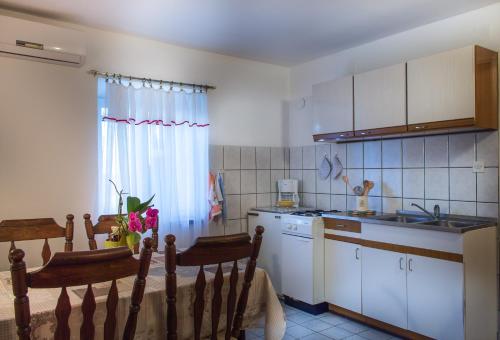 a kitchen with white cabinets and a table and chairs at Apartman Đina in Risika