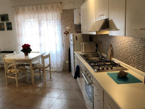 eine Küche mit einem Herd, einer Spüle und einem Tisch in der Unterkunft House Orsa Maggiore by Holiday World in Bordighera