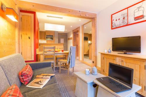 a living room with a couch and a laptop on a table at Résidence Pierre & Vacances Premium les Crets in Les Allues