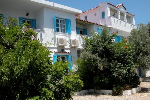 a large white house with blue windows and bushes at Pelagia in Marathokampos