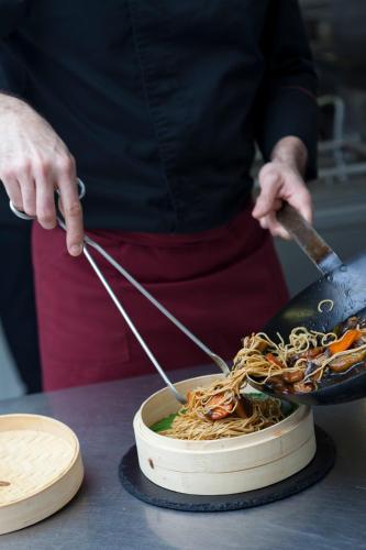 a person is preparing noodles in a pan at URH Ciutat de Mataró in Mataró