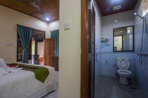 a bedroom with a bed and a bathroom with a toilet at Masna House in Ubud