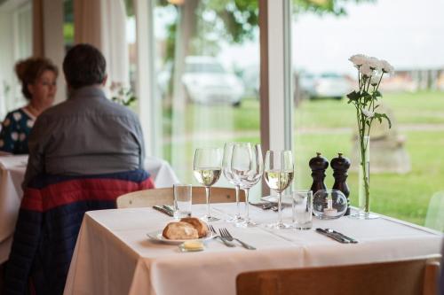 a table with wine glasses and a plate of food at Strandhotel Klinten in Rødvig