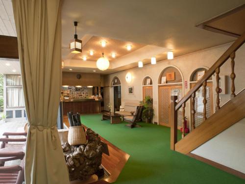 a living room with a staircase and green carpet at くさつのお宿 清重館 Kiyoshigekan 素泊りの宿 in Kusatsu