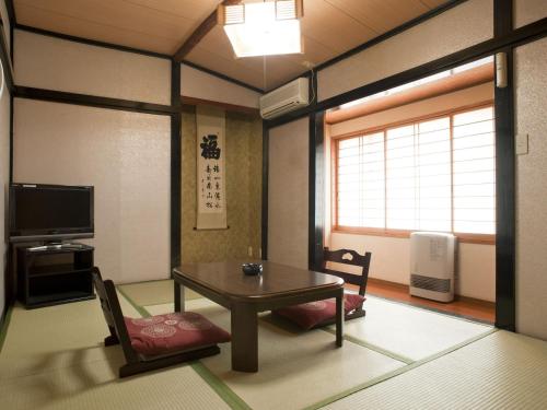 sala de estar con mesa, sillas y TV en Kiyoshigekan, en Kusatsu