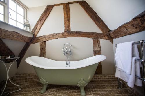 uma banheira na casa de banho com vigas de madeira em The Porch House em Stow on the Wold