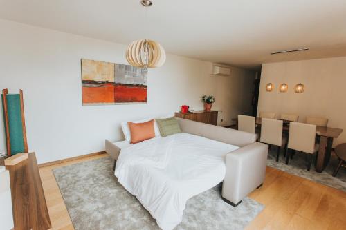 a bedroom with a white bed and a dining room at Magnolia Apartment in Geres