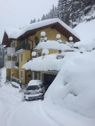 a car parked in front of a house covered in snow at Landhaus Gabriele in Filzmoos