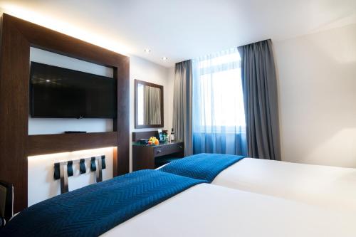 a bedroom with a large bed and a television at Montcalm Chilworth Townhouse, Paddington in London