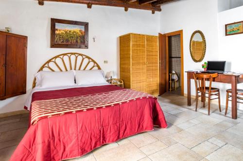 a bedroom with a bed with a red blanket and a desk at B&B Borgo San Martino in Monopoli