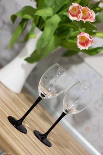 two wine glasses on a table with a vase with flowers at ClickTheFlat Żurawia Street Apart Rooms in Warsaw