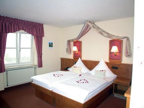a bedroom with a large bed with white sheets and a window at Hotel "Untere Mühle" in Schwabmühlhausen