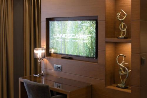 a living room with a television and a table with a lamp at Family Hotel Strannopriemnitza in Oreshak