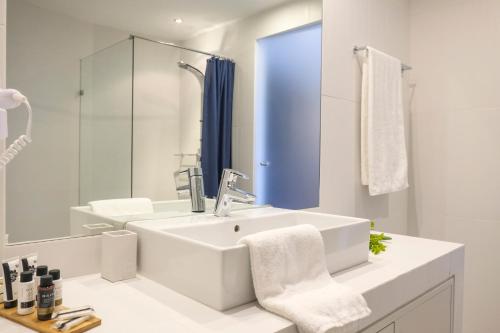 a white bathroom with a sink and a mirror at Lotus Inn in Athens