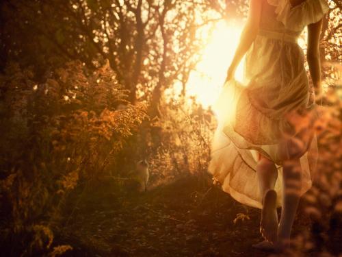 a woman in a white dress walking through a forest at Romantic Boutique Hotel & Spa in Panevėžys