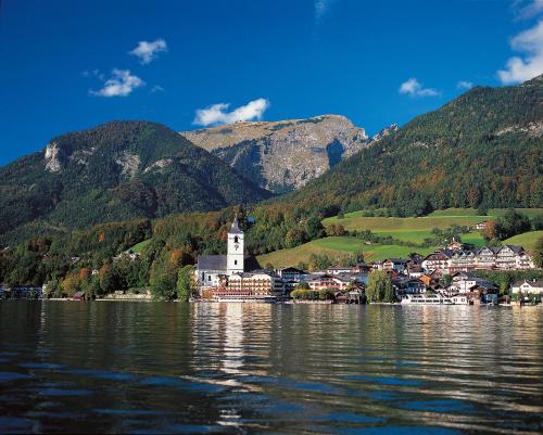 une ville sur l'eau avec des montagnes en arrière-plan dans l'établissement Haus Alpenrose, à Sankt Wolfgang im Salzkammergut
