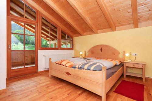 a bedroom with a wooden bed in a room with windows at Haus Traudi in Nova Ponente