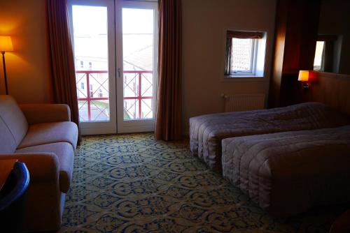 a hotel room with a bed and a couch and a window at Montra Odder Parkhotel in Odder