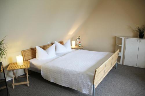 een slaapkamer met een groot bed met witte lakens en kussens bij Pension "Zur Steilküste" in Boltenhagen