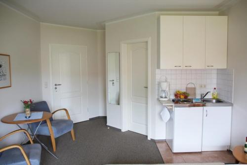 - une cuisine avec des placards blancs, une table et un évier dans l'établissement Pension "Zur Steilküste", à Boltenhagen