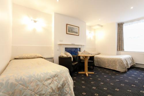 a hotel room with two beds and a table at Jesmond Hotel in London