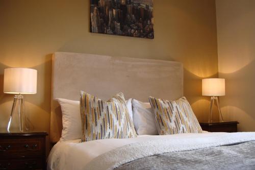 a bedroom with a bed with pillows and two lamps at Pinfield Boutique Hotel in Slough
