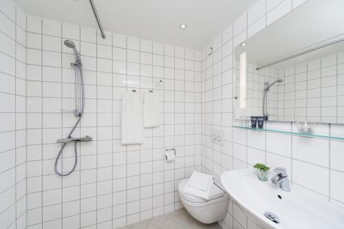 a white tiled bathroom with a shower and a toilet at Hotel Klinten in Rødvig