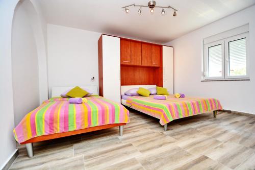 2 łóżka w pokoju z białymi ścianami i drewnianą podłogą w obiekcie Gabi 2 w mieście Zadar