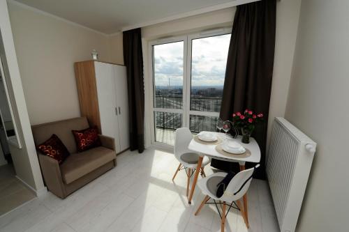 een woonkamer met een tafel en stoelen en een raam bij Romantic Sky Apartment- 15th floor in Krakau
