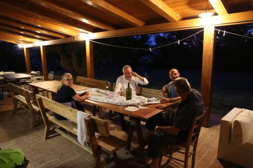 a group of people sitting around a wooden table at Casale Talevi in Cartoceto