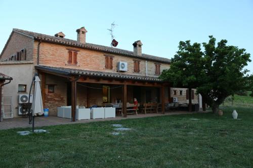 a large brick building with a tree in front of it at Casale Talevi in Cartoceto