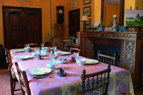 a dining room table with a pink table cloth and a fireplace at Domaine de Beauvilliers in Chaumontel