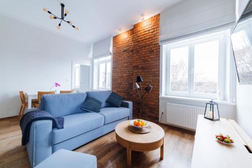 a living room with a blue couch and a brick wall at Way2Stay Old Town in Kraków