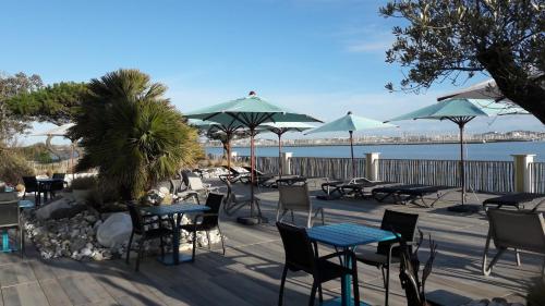 a deck with tables and chairs and umbrellas at Hôtel Les Brises in La Rochelle