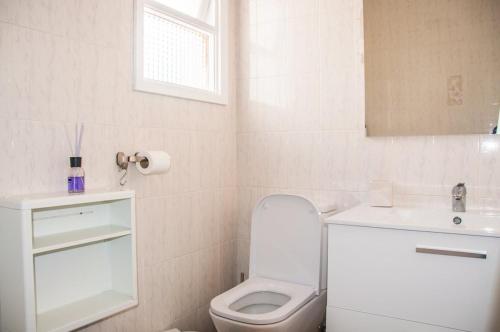 La salle de bains blanche est pourvue de toilettes et d'un lavabo. dans l'établissement Cozy vacation apartment in Los Gigantes, à Acantilado de los Gigantes