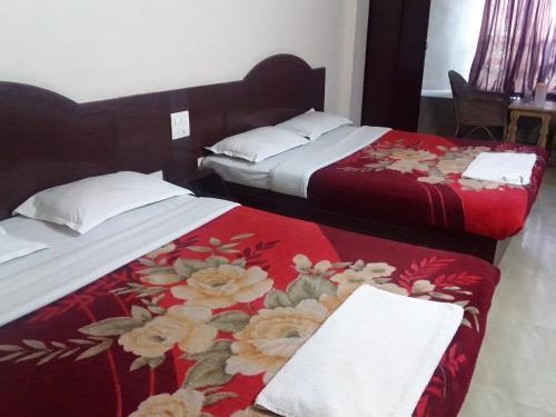 two beds in a hotel room with red and white blankets at Jays Inn in Munnar