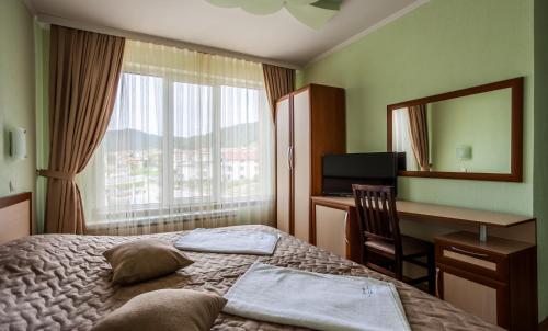 a hotel room with a bed and a desk and a mirror at Семеен хотел "Елеганс" - Борино in Borino